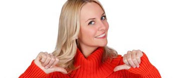 Blonde Frau mit rotem Pullover lächelt und zeigt mit den Daumen auf sich selbst.