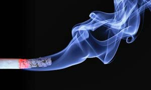 Zigarette mit blauem Rauch auf schwarzem Hintergrund